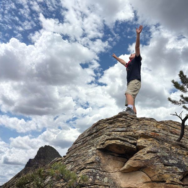 A child confidently speaking affirmations in a beautiful mountain meadow setting